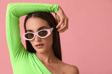 Beautiful young woman in stylish sunglasses on pink background