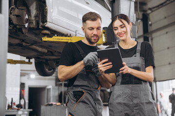 Young expert female inspects repair checklist with automotive mechanic worker partner, quality...