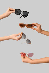 Female hands with different stylish sunglasses on grey background