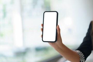 Businesswoman is showing a smartphone with a blank screen in an office environment