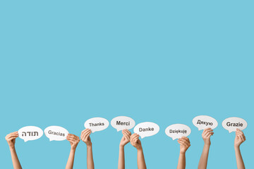 Female hands holding speech bubbles with text THANK YOU in different languages on blue background