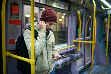 Man, online and phone for music on bus journey, travel and social media scroll on public transport. Male person, streaming and earphones in metro vehicle, New York traveler and trip in urban traffic