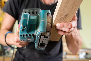 A carpenter grinds an oak part with a grinding machine