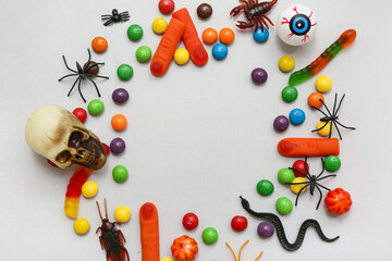 Frame made of different candies and decorations for Halloween on grey background