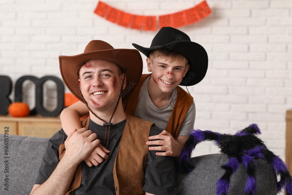 Poster father with his son dressed for halloween as cowboys hugging at home