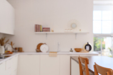 Blurred view of light kitchen with white counters and shelf
