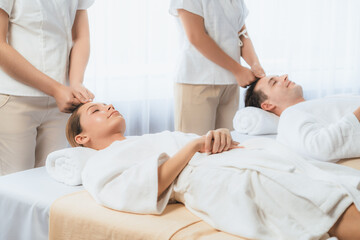 Fototapeta premium Caucasian couple enjoying relaxing anti-stress head massage and pampering facial beauty skin recreation leisure in dayspa modern light ambient at luxury resort or hotel spa salon. Quiescent