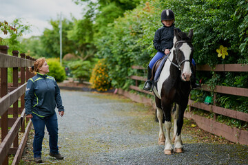 Obraz premium Girl, horse and riding in countryside for equestrian, development and learning with instructor. Teenager, animal and pet on farm for workout, teaching and fitness with training, exercise and helmet