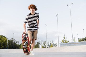 Active redhead caucasian curly teen school boy guy teenager skater in casual riding on skateboard...