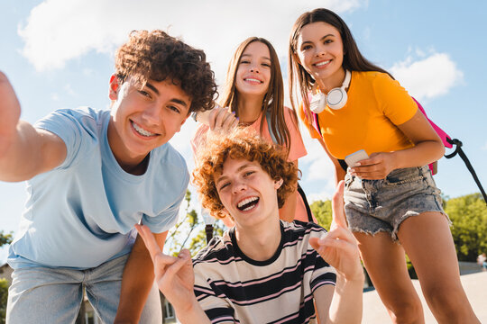 Happy smiling group of teenagers high school pupils friends classmates college students boys and girls with bags hanging out in park nature street outside take selfie shot picture photo having fun