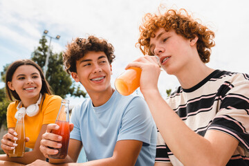 Close up shot of redhead curly teen boy drinking orange fresh juice lemonade spending time with...
