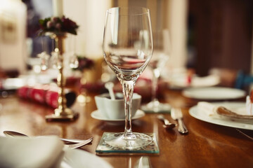 Drink, glassware and dinner with party, celebration event with glass, Christmas and lunch at home for holiday. Table setting, alcohol and crockery for fine dining, December decoration and house