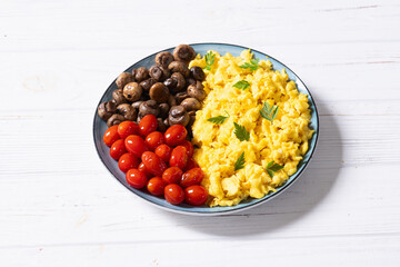 Homemade scrambled eggs with mushrooms and cherry tomatoes