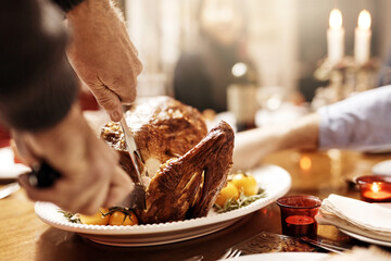 Hands, dinner and cutting turkey for thanksgiving celebration, festive holiday or feast. People, food and carving meat in home for social gathering, event or party with family eating together closeup