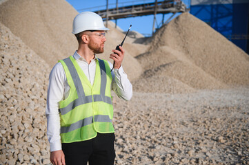 A worker in a helmet stands at a stone crushing plant
