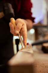 Handyman carving wood using chisel and hammer in carpentry shop, enjoying diy hobby. Man using traditional crafting process to shape wooden pieces with tools, making wood art, close up shot