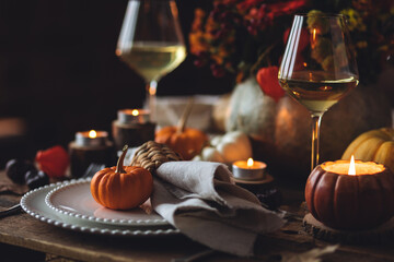 Atmospheric autumn elegant beautiful table setting with pumpkins for a wedding or thanksgiving family celebration. Fall decoration countryside rustic style, cozy home atmosphere , candles, wine