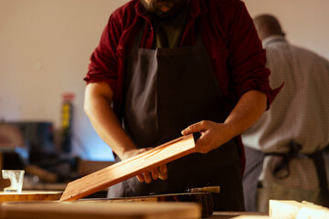 Cabinetmaker picking paintbrush to apply varnish on wooden surface, prevent damage and provide...