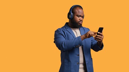 Smiling african american man listening to music on bluetooth headphones connected to smartphone....