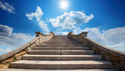 Fototapeta premium Old stone stairs rises to haven, blue sky with white clouds, magic steps leading upwards.