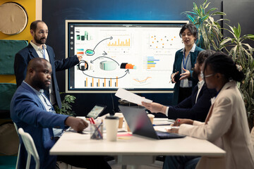 Team of partners working on resource allocation initiatives during a meeting, making important budgeting decisions to corelate with enterprise objectives. Coworkers review strategies.