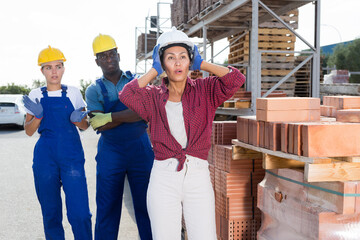 Woman hands hold her head, she has problems at work at a hardware store warehouse