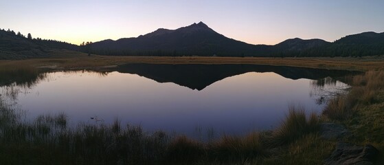 Obraz premium Mountain Silhouette Reflected in a Calm Lake at Dusk