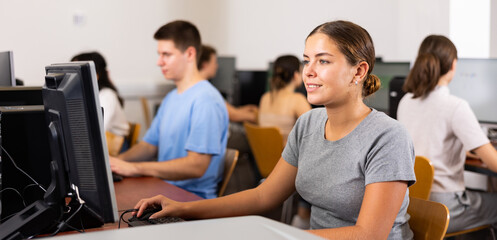 Young caucasian woman using computer in classroom and smiling. Female student using PC.