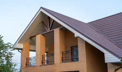 A contemporary house features a sloped roof and stylish balcony, blending classic and modern architectural elements under a clear sky