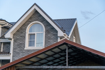 A charming house features a sloped roof, detailed facade, and expansive windows, showcasing suburban living at twilight