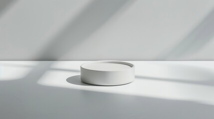 A round white dish sits on a smooth surface, surrounded by soft shadows, creating a serene and minimalist aesthetic with natural light filtering through