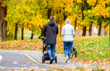 Obraz premium A married couple rolls a baby stroller in a city Park 