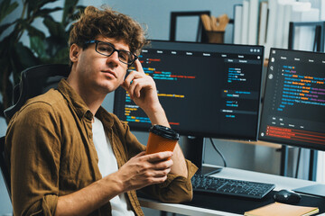 Working IT developer looking at camera holding coffee cup with online software at modern office on...