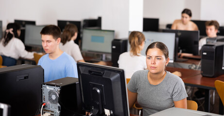 Woman sitting at desk in computer class and using PC, learning to use software.