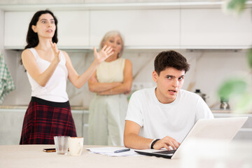 Fototapeta premium Mom and young wife scold her husband about financial problems. Husband is not satisfied with the calculations of financial results