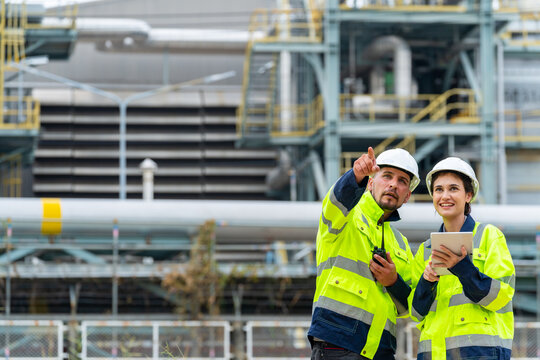 Man and woman petrochemical engineer teamwork meeting discussion at petroleum oil refinery industry area. Industrial factory technician worker working maintenance manufacturing energy power gas system
