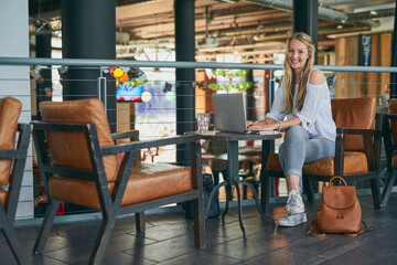 Happy woman, portrait and author with laptop at cafe for online browsing, content creation or digital writing. Young, female person or journalist with smile on computer for connection at coffee shop