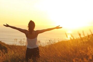 Woman with Outstretched Arms Standing on a Grassy Hill Overlooking the Ocean at Sunrise, Bathed in Warm Golden Light, Capturing a Serene and Joyful Moment of Freedom and Nature's Beauty