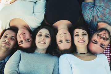 Happy people, portrait and lying above with group for picnic, bonding or social gathering together. Top view, young friends or men and women relaxing on mat for chilling, holiday or outdoor weekend