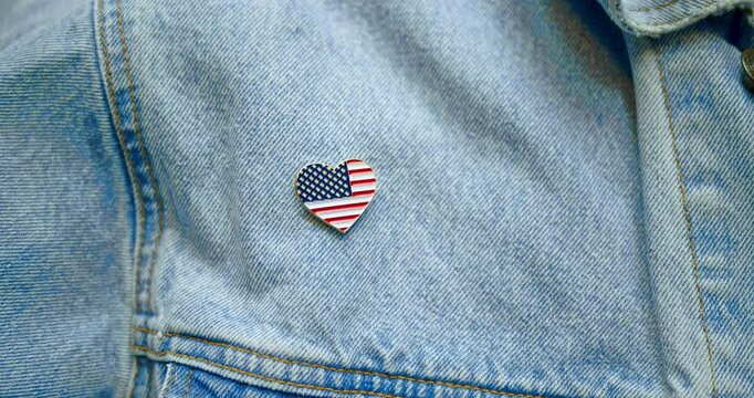 American blue collar worker pinning shiny lapel pin in the shape of a heart with the US American flag. Celebrating patriotism, Labor Day, manufacturing in America, or another patriotic USA holiday.