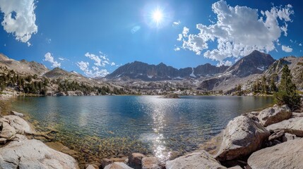 Obraz premium Serene Mountain Lake with Rocky Shores and Sunlit Clouds