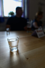 Chaining alcohol into a glass with a man and a woman in the background.