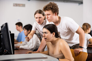 Young boy and girls student emotionally reacting while studying at computer in college technology...