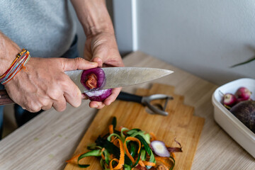 a man peeling off a variety of vegetables such as cucumber, onion, carrot, into the cutting board...