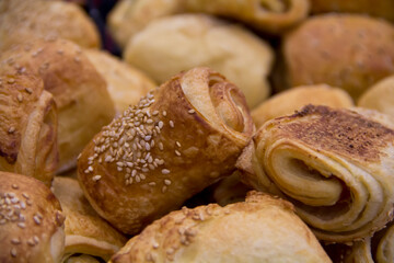 Bread rolls with sesame seeds piled in a bakery shop, close-up.