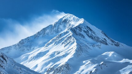 Majestic snow-covered mountain peak under a clear blue sky, showcasing the beauty of winter landscapes and the serenity of untouched nature.