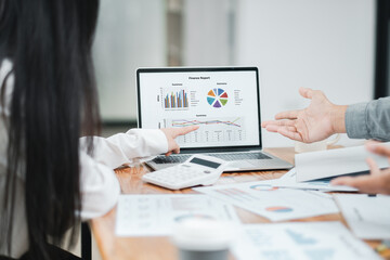 Team members discussing financial data displayed on a laptop during a business meeting in a modern office setting.