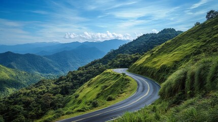 A scenic mountain road winding through lush green hills with a clear blue sky overhead, showcasing the beauty and serenity of a high-altitude drive.