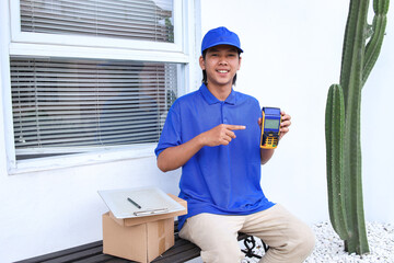 Asian deliveryman holding POS terminal. Delivery payment concept.