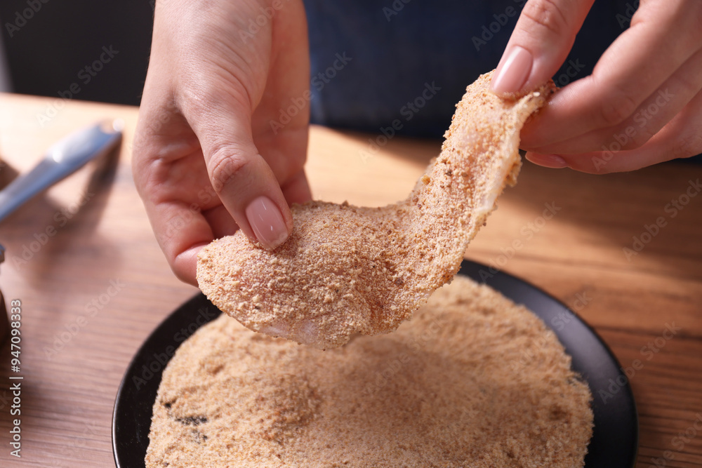 Canvas Prints making schnitzel. woman coating slice of meat with bread crumbs at wooden table, closeup